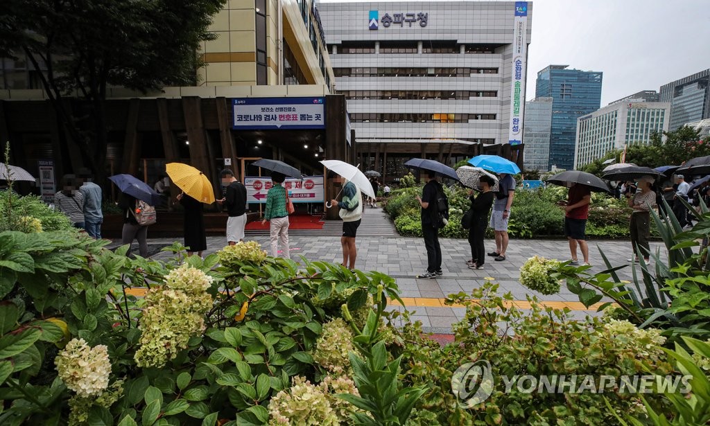 9月7日，在设于首尔松坡区卫生站的筛查诊所，市民们撑伞排队等待接受病毒检测。 韩联社