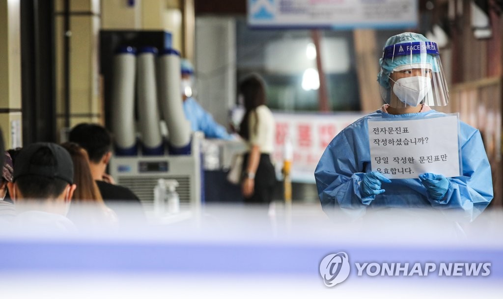 资料图片：9月7日，在设于首尔松坡区卫生站的筛查诊所，医务人员手举检测指南。 韩联社