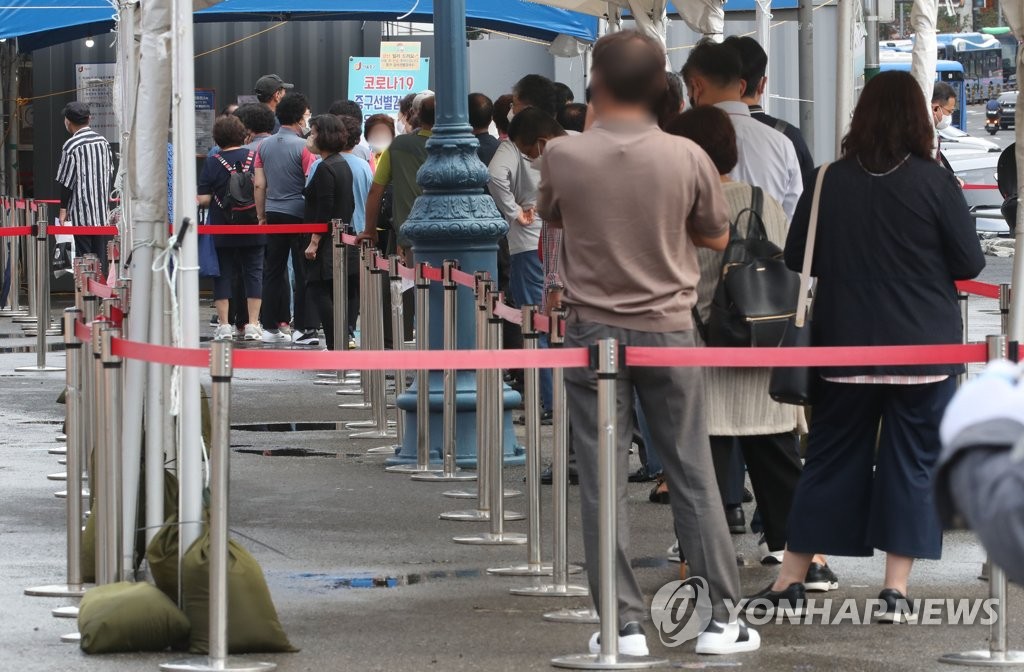 资料图片：9月8日，在设于首尔站的筛查诊所，市民们排长龙等待接受病毒检测。 韩联社