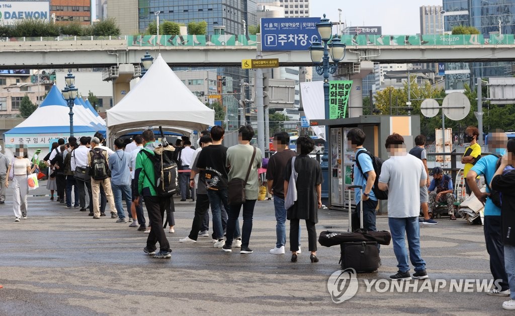 资料图片：9月13日，在首尔火车站广场的临时筛查诊所前，人们排队等待检测新冠病毒。 韩联社
