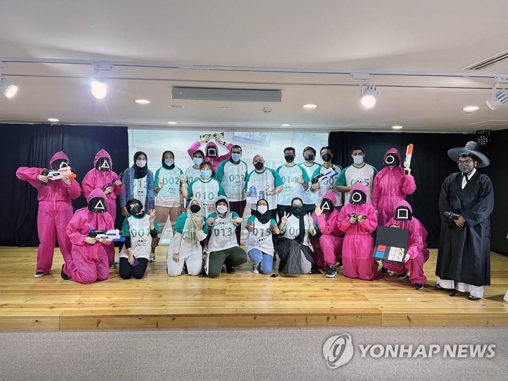 当地时间2021年10月12日，在阿联酋阿布扎比的韩国文化院，人们体验奈飞韩剧《鱿鱼游戏》中的游戏并拍照留念。 韩联社/驻阿联酋韩国文化院供图（图片严禁转载复制）