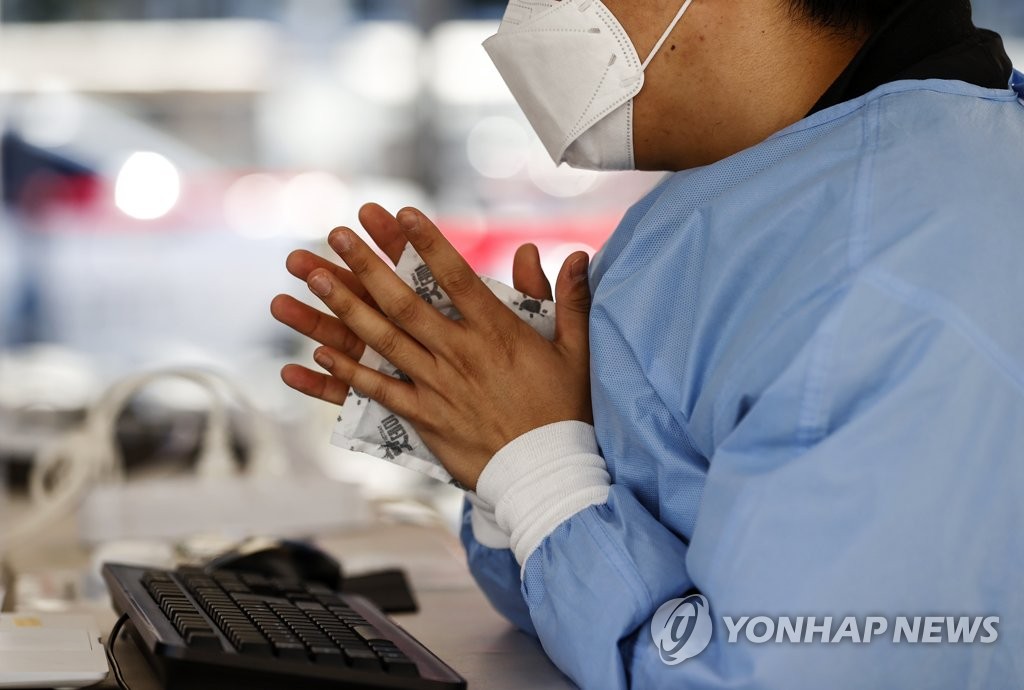 资料图片：10月17日，在首尔火车站的新冠临时筛查诊所，工作人员正在用暖贴取暖。 韩联社