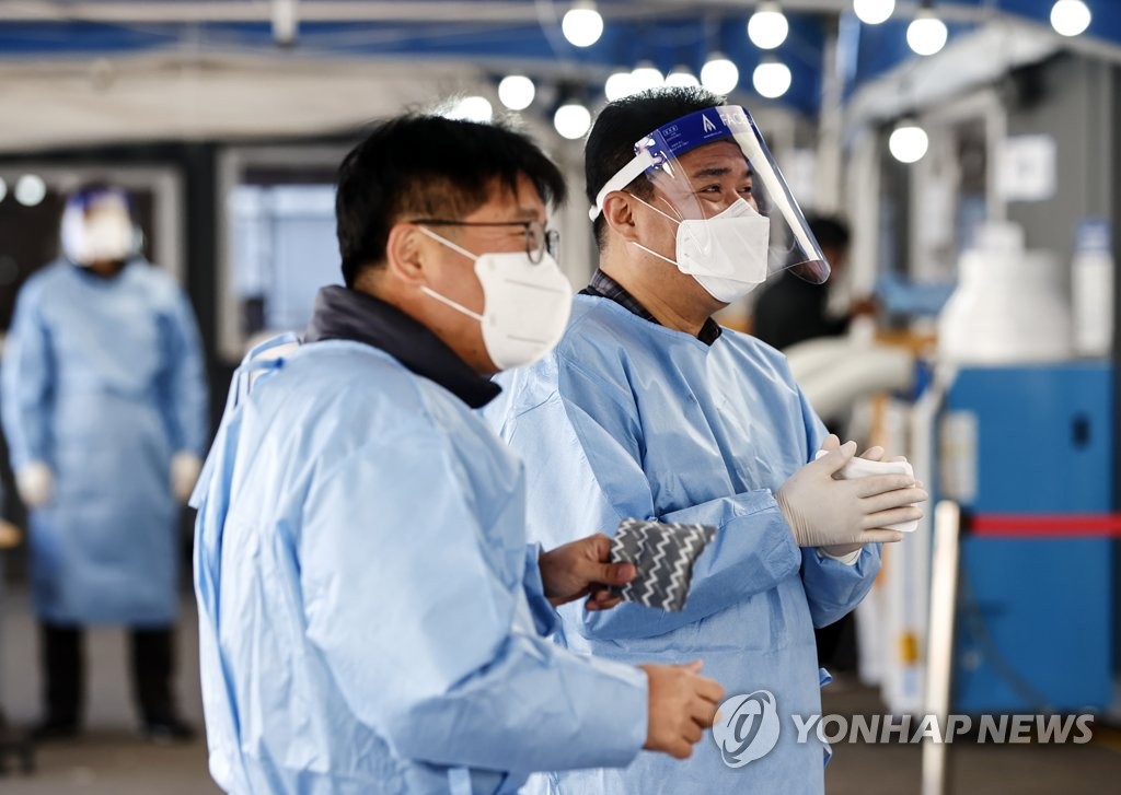 资料图片：10月17日，在设于首尔站的临时筛查点，医务人员一边暖手，一边交谈。 韩联社