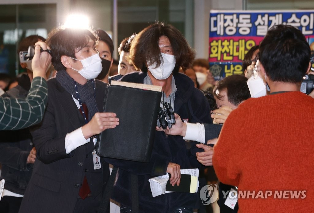 10月18日，在仁川国际机场，京畿道城南市大庄洞地产开发项目涉腐案核心人物、律师南旭（中）下机后被记者包围。 韩联社