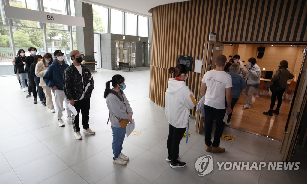 资料图片：1月18日，在设于首尔中央大学的疫苗接种中心，外国留学生排队接种疫苗。 韩联社