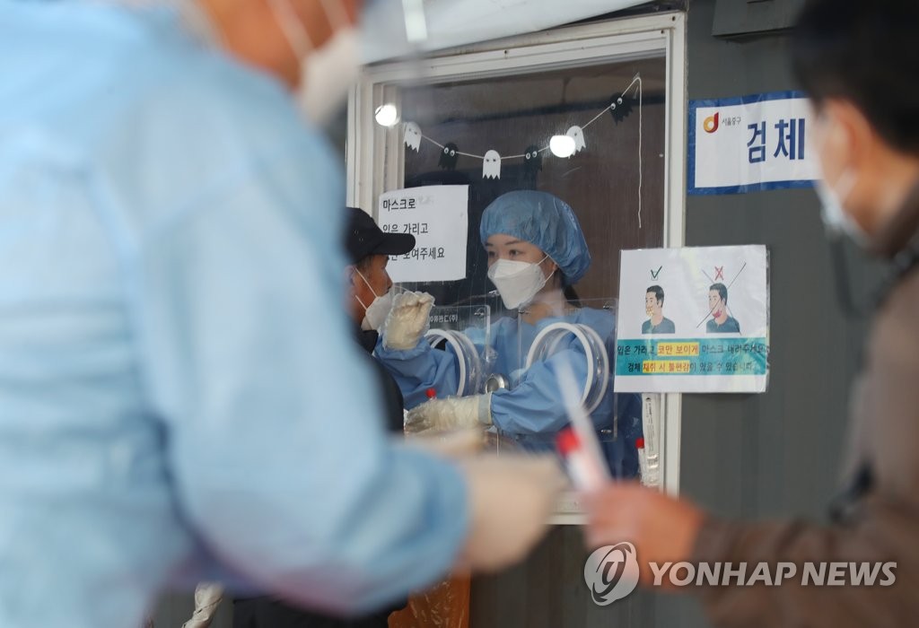 资料图片：10月24日，在首尔站的临时筛查诊所，工作人员正为一市民做核酸检测。 韩联社