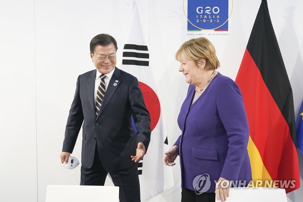 当地时间10月31日，在意大利罗马，韩国总统文在寅（左）和德国总理默克尔借二十国集团（G20）领导人峰会之机举行双边会谈。图为文在寅和默克尔步入会场。 韩联社