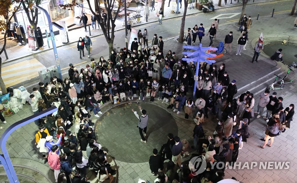 资料图片：11月7日晚，在韩国本月1日启动“与疫共存”模式第一阶段后迎来的首个周末，首尔弘益大学附近街头表演吸引路人围观。 韩联社