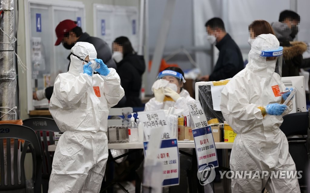 资料图片：11月10日，在首尔市一新冠筛查诊所，医务人员正在擦防护面罩上哈气凝结的水珠。 韩联社