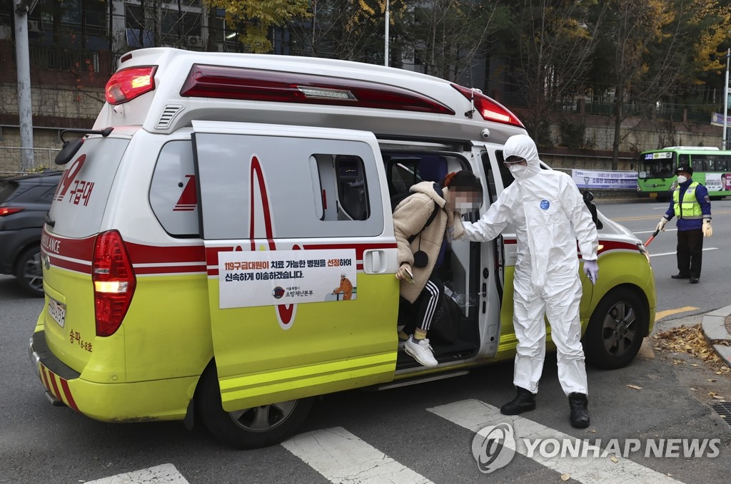 资料图片：11月18日，在首尔松坡工业高中，一名高考生走下救护车准备进入隔离考生专用考场。 韩联社