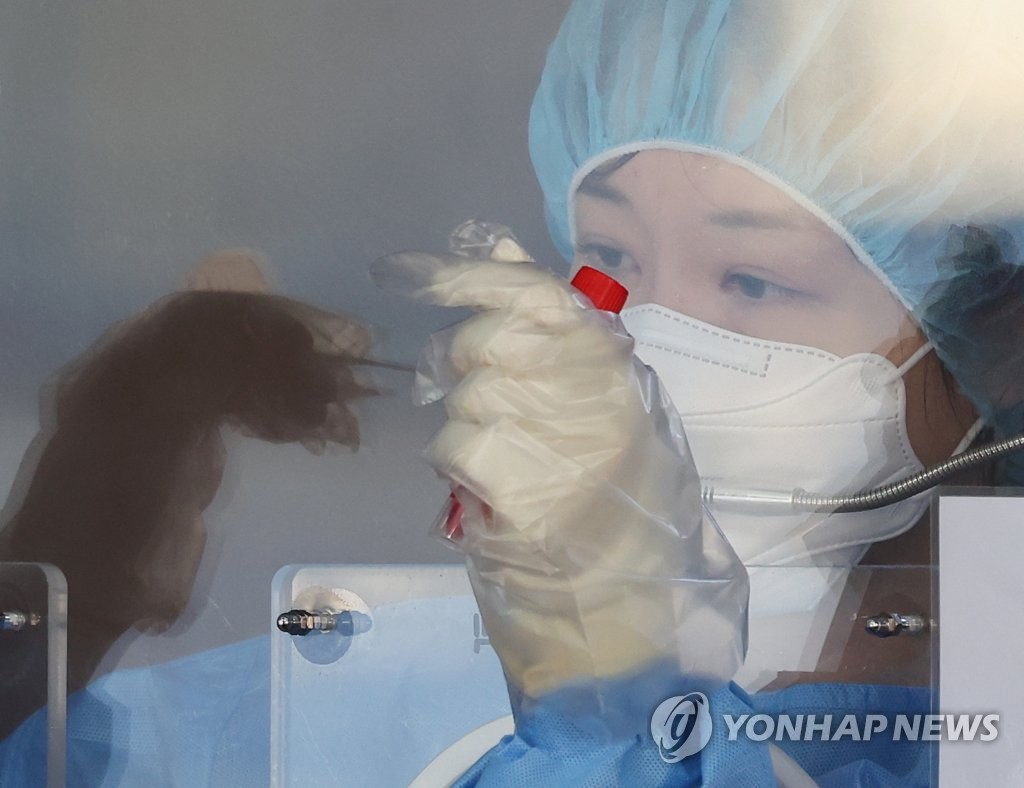 资料图片：11月26日，在设于首尔站的临时筛查诊所，医务人员取样。 韩联社