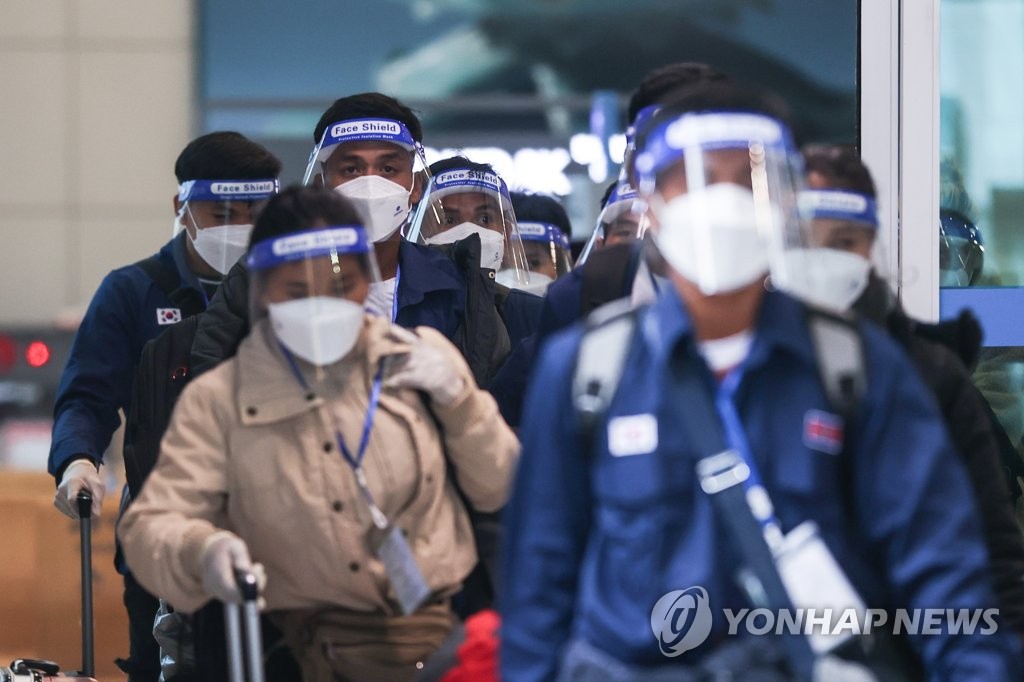 11月30日，在仁川国际机场，一群身穿防护服的外国人入境。韩国防疫部门日前禁止来自南非等八国的外国人入境韩国，以防新冠新变异毒株“奥密克戎”流入社区。 韩联社