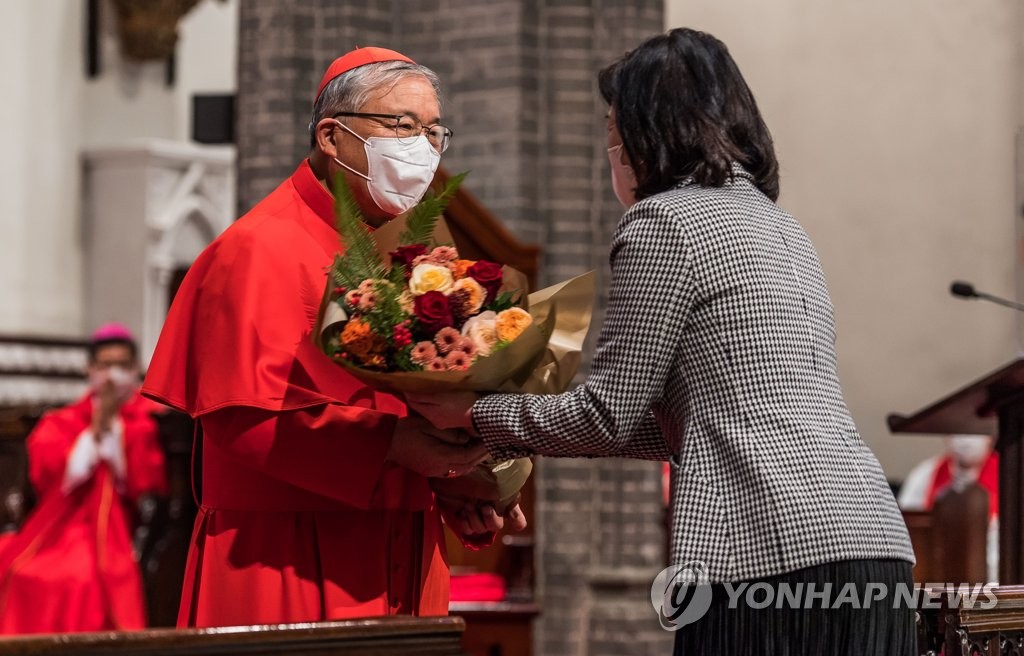 11月30日，在首尔明洞天主教堂，首尔总教区区长、枢机主教廉洙政的离任弥撒举行。图为廉洙政（左）从教徒的手中接过花束。 韩联社/联合摄影记者团