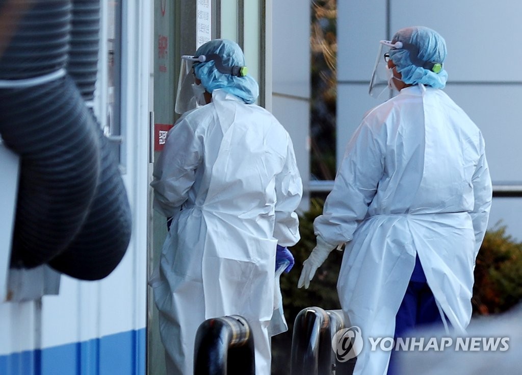 12月2日，在仁川市收治奥密克戎确诊病例的医院前，两名医护人员严阵以待。 韩联社