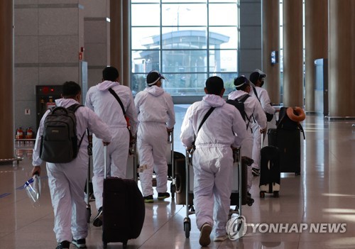 资料图片：12月6日，在仁川国际机场，身着防护服的入境人员前往隔离设施。 韩联社