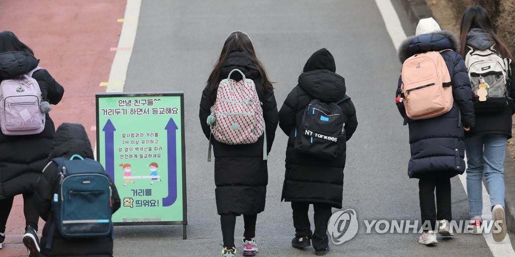 资料图片：韩国一所小学的学生们背书包上学。 韩联社