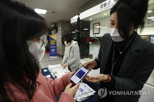 资料图片：工作人员正在确认防疫通行证。 韩联社