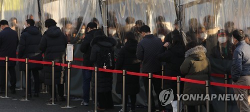 资料图片：12月20日，在设于首尔站广场的临时筛查点，市民们排长队等待接受新冠检测。 韩联社