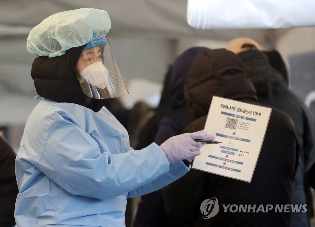 资料图片：12月26日，在首尔松坡区卫生站的筛查诊所，医务人员为市民指引接受病毒检测。 韩联社