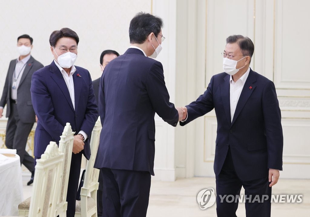 12月27日，在青瓦台，韩国总统文在寅邀请六大企业集团掌门共进午餐。图为文在寅（右一）与三星电子副会长李在镕握手致意。 韩联社