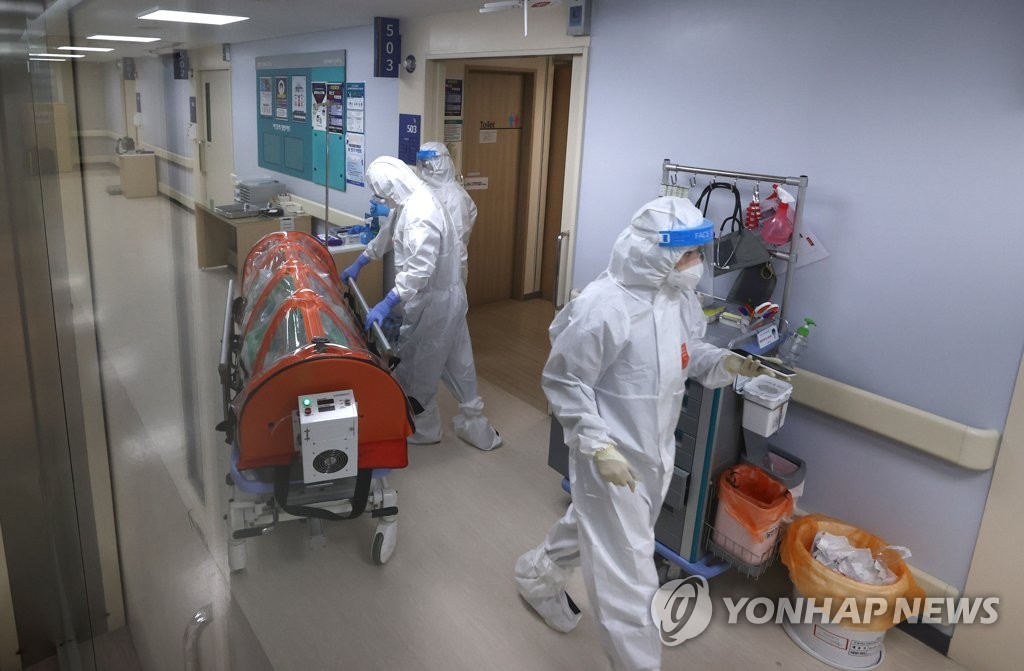 资料图片：12月28日，在首尔市移出新冠定点医院，医务人员正在护送新冠患者。 韩联社