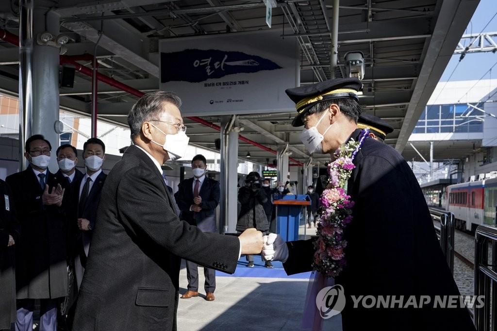 12月28日，在蔚山市太和江站，韩国总统文在寅出席东南圈4条铁路建设项目开通仪式。图为文在寅（左）与驾驶员握手致意。 韩联社