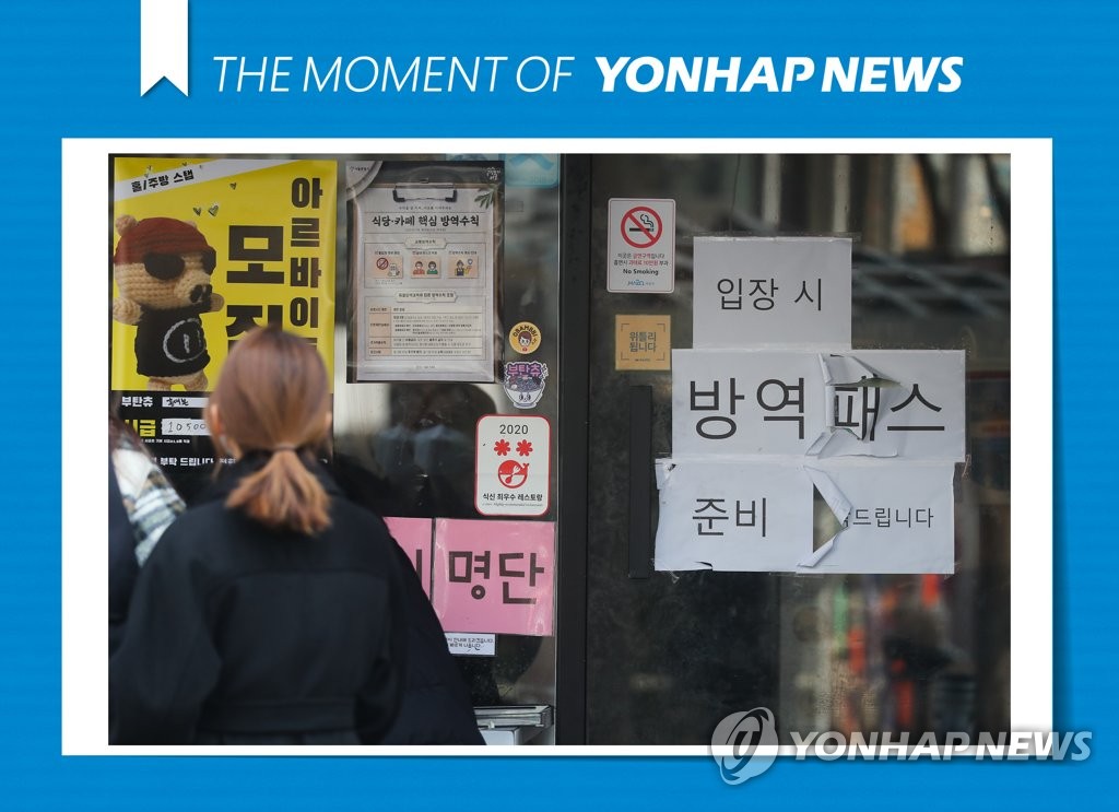 资料图片：商店贴出有关实施防疫通行证的公告。 韩联社