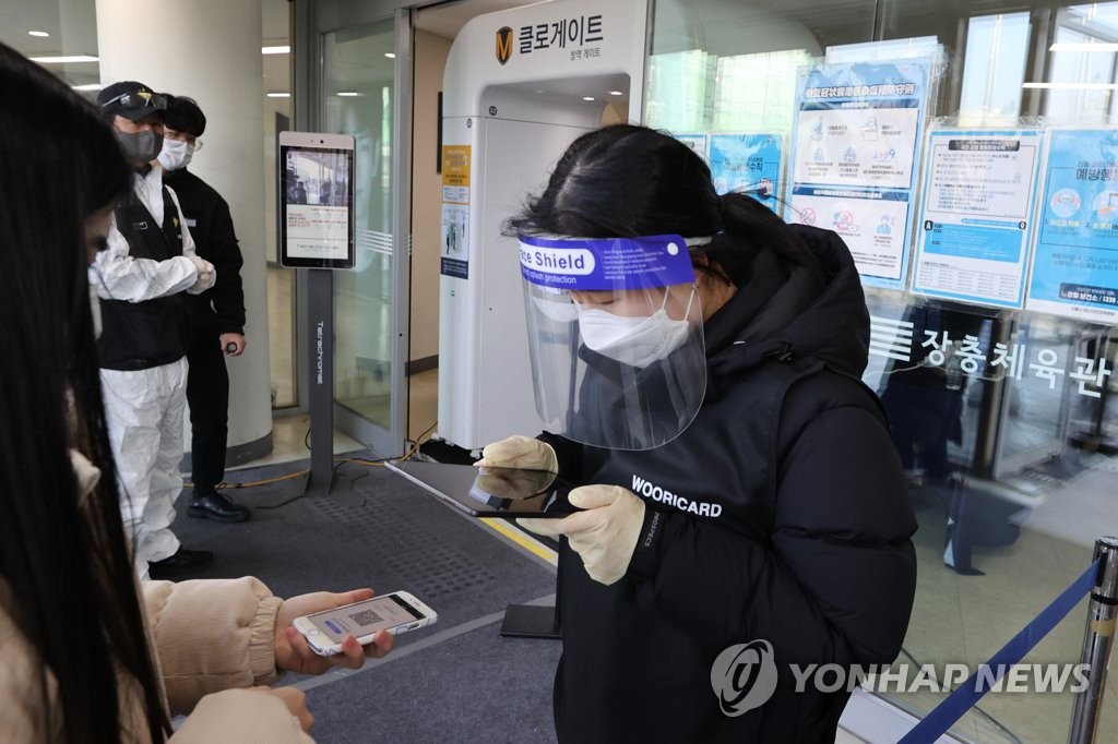 资料图片：1月2日，在首尔奖忠体育馆，工作人员确认防疫通行证。 韩联社