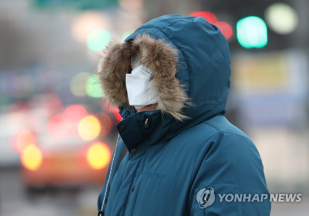 资料图片：1月7日上午，在首尔世宗大街十字路口，一名市民裹着厚实的冬装出行。当天，首尔早晨最低气温降至零下6摄氏度。 韩联社