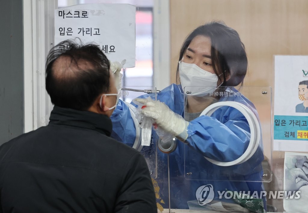 资料图片：1月9日，在首尔站临时筛查诊所，医务人员（右）为市民进行核酸采样。 韩联社