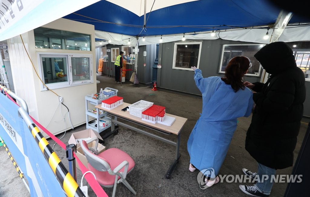 1月9日上午，在首尔市中区首尔站核酸采样点，工作人员指引市民接受检测。 韩联社