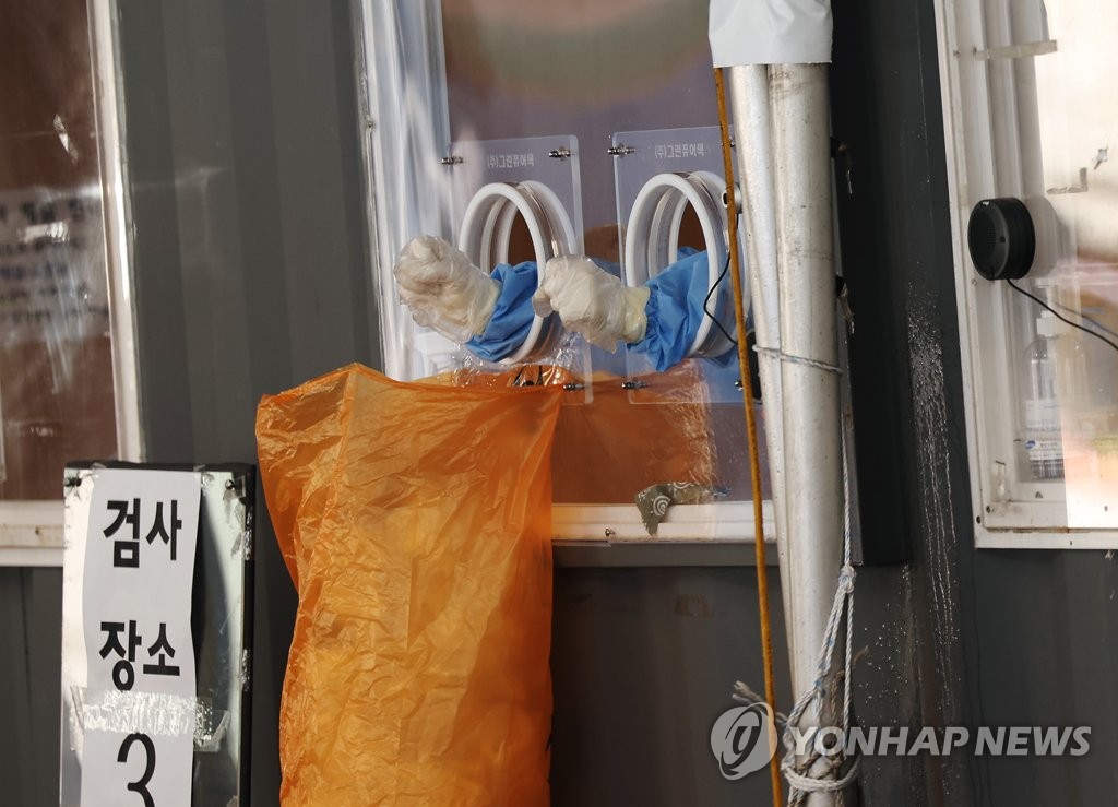 资料图片：1月11日，在首尔站广场，核酸采样人员等待受检者。 韩联社