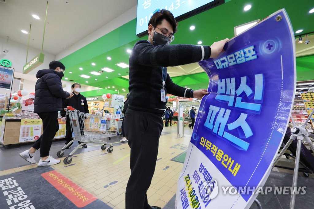 资料图片：一超市工作人员摆放实施防疫通行证的通知。 韩联社