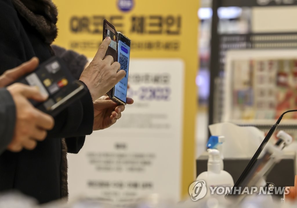 资料图片：消费者在一家大型超市门口扫码入场。 韩联社