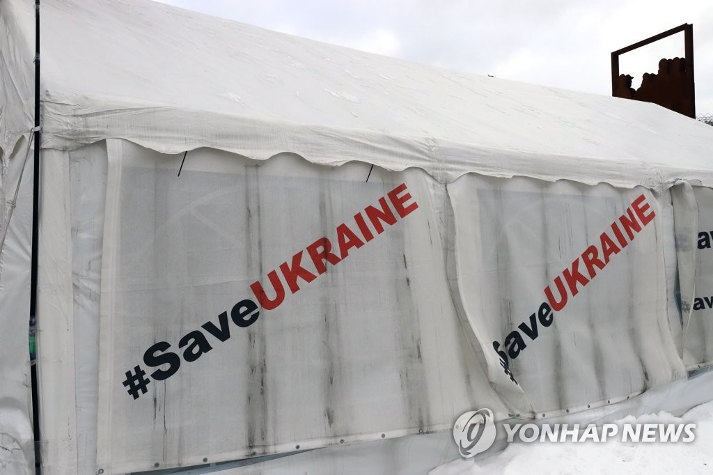 资料图片：当地时间1月18日，在乌克兰首都基辅独立广场的大棚上印着“拯救乌克兰”的字样。 韩联社