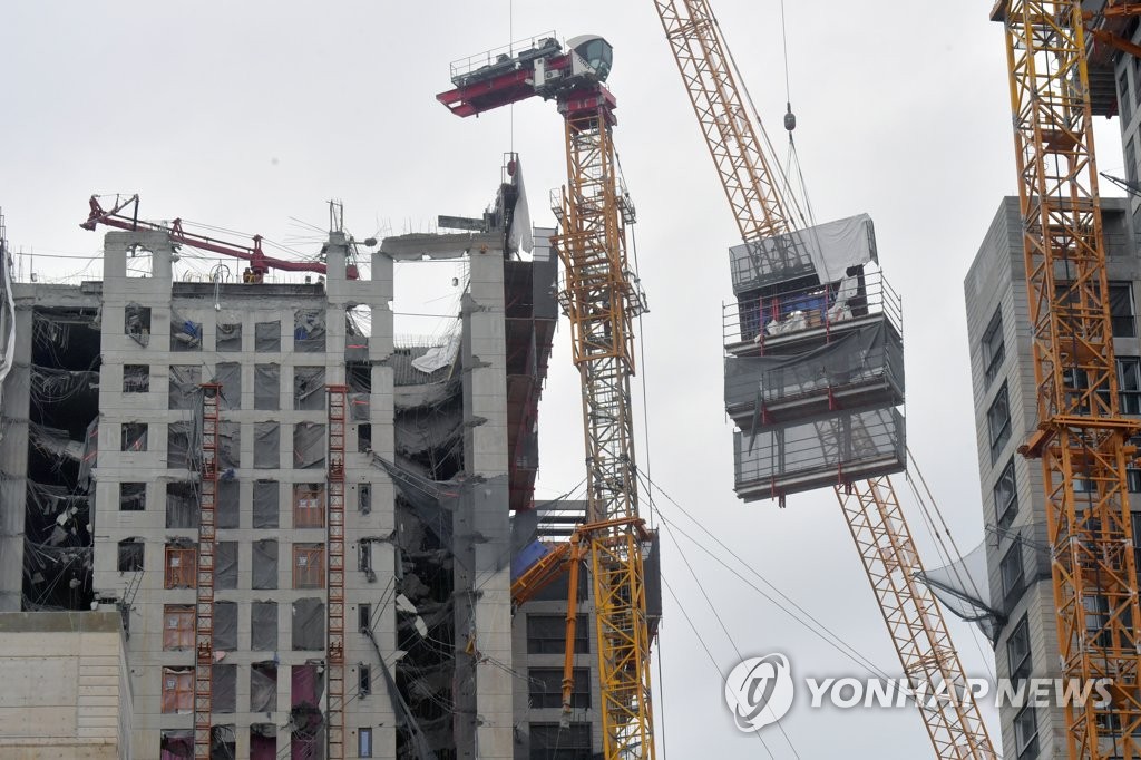 1月22日上午，在光州市西区花亭I-PARK高层住宅楼坍塌事故现场，救援人员正在拆除导轨式爬架。倾斜的塔式起重机可能继续拆解。 韩联社