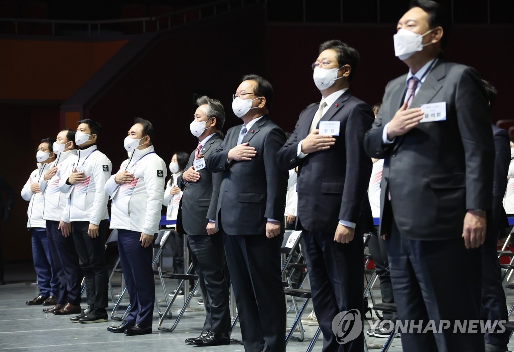 1月25日，韩国代表团成团仪式在首尔奥林匹克公园奥运会大厅举行。图为韩国国务总理金富谦（右三）、最大在野党国民力量总统优选人尹锡悦（右一）和韩国代表团向国旗敬礼。 韩联社