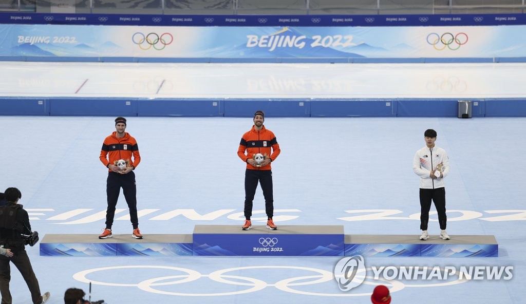 2月8日，在北京国家速滑馆举行的2022年北京奥运会速滑男子1500米比赛上，韩国选手金慜锡用时1分44秒24，摘得铜牌。图为金慜锡（右一）手捧金色版“冰墩墩”站上领奖台。 韩联社