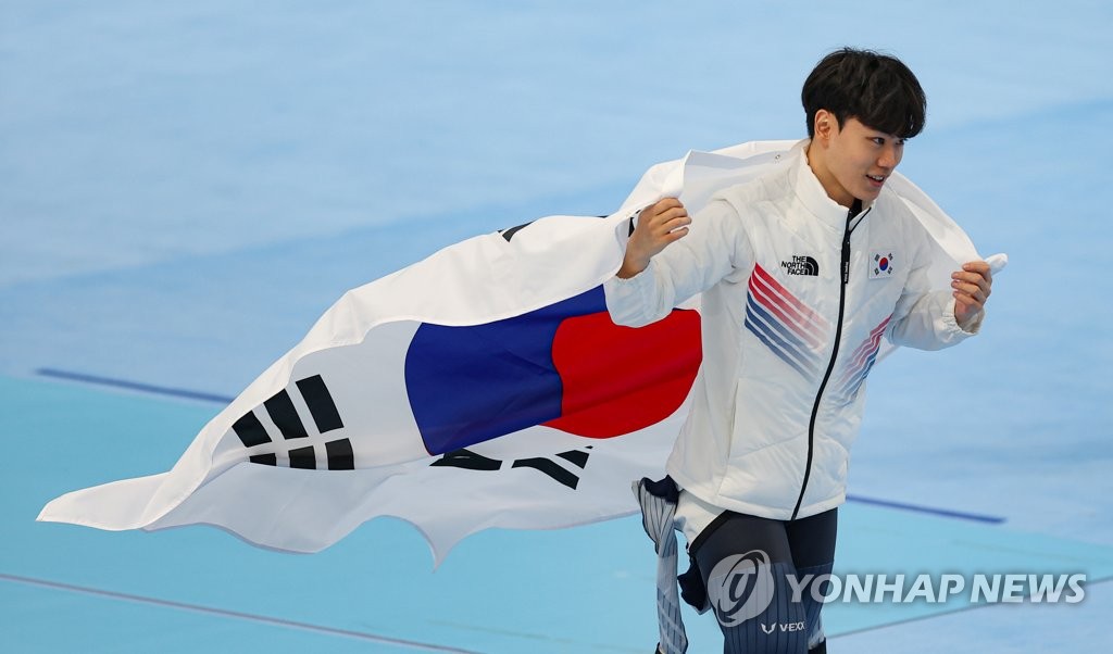 2月8日，在北京国家速滑馆举行的2022年北京奥运会速滑男子1500米比赛上，韩国选手金慜锡用时1分44秒24，摘得铜牌。这也是韩国代表团在本届冬奥会上收获的首枚奖牌。图为金慜锡身披国旗庆祝。 韩联社
