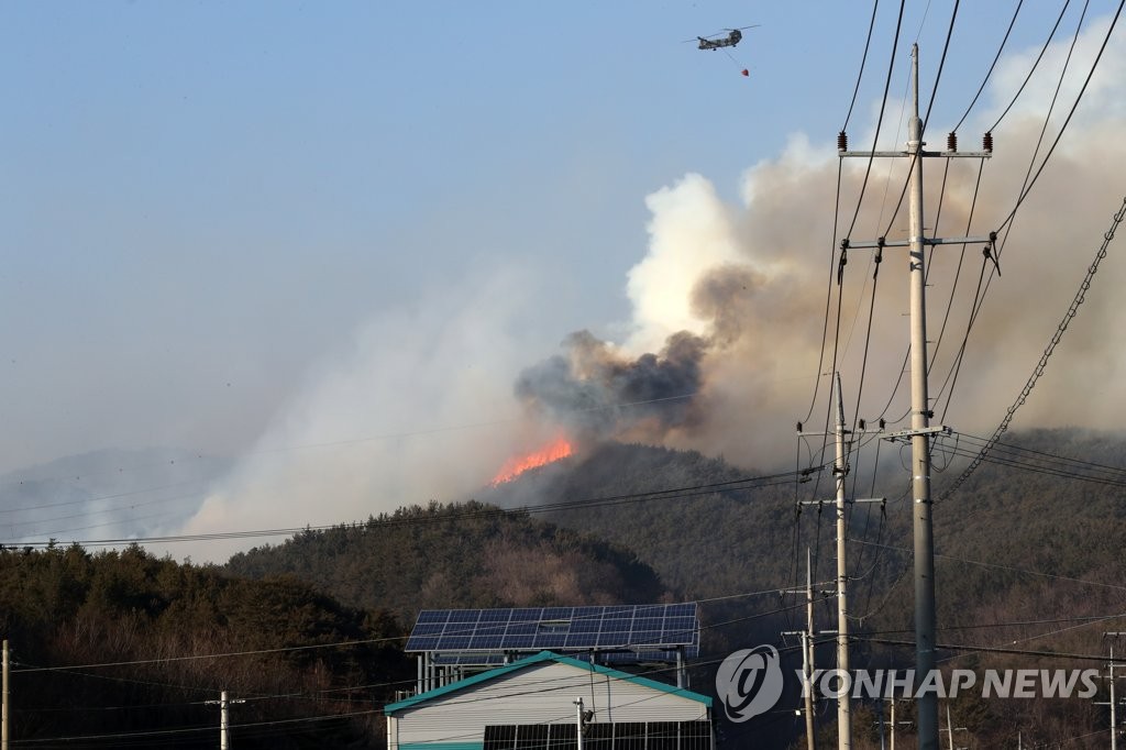 2月16日，在在庆尚北道盈德郡盈德邑的山火现场上空，一架直升机正在进行吊桶洒水