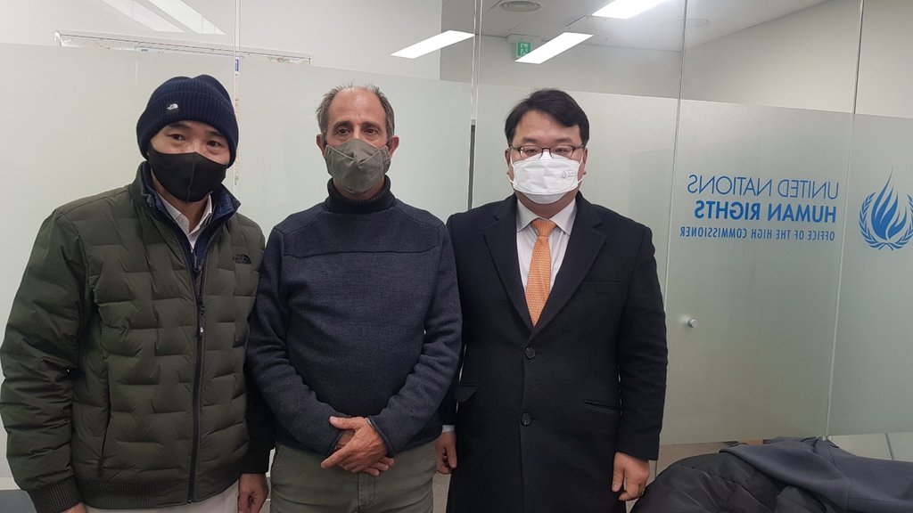 资料图片：金塔纳（中）与被朝军枪杀的渔政公务员家属李来真（左） 韩联社