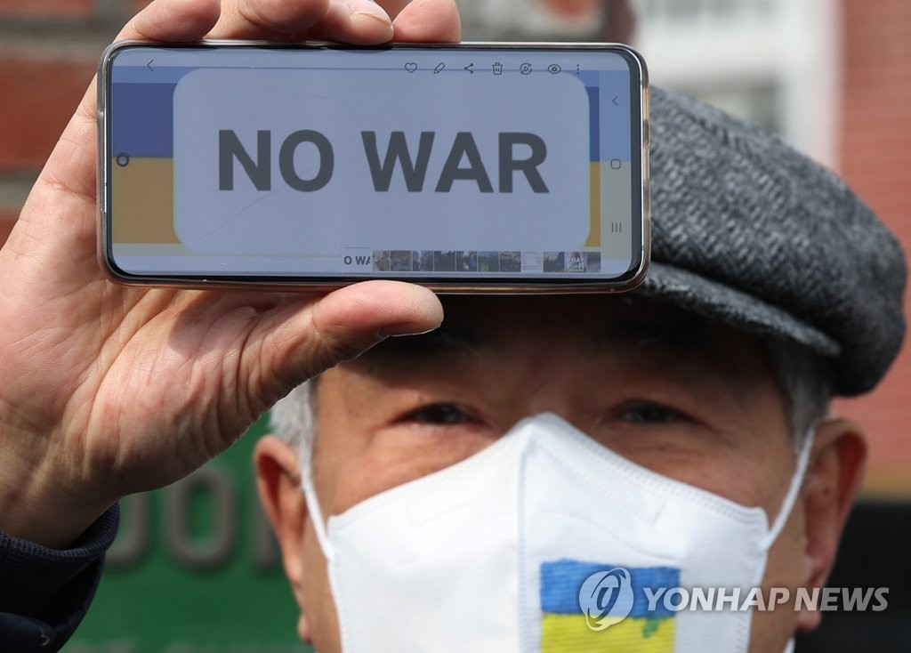 资料图片：2月28日，在位于首尔市中区的俄罗斯驻韩大使馆附近，韩国民团和旅韩乌克兰人举行反战示威，谴责俄罗斯进攻乌克兰。图为一名示威参加者在手机屏幕上打出“反对战争”的标语。 韩联社