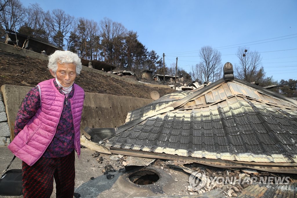 3月6日，在庆尚北道蔚珍郡，一名居民看到自家被山火烧毁的情景后难掩惆怅。 韩联社