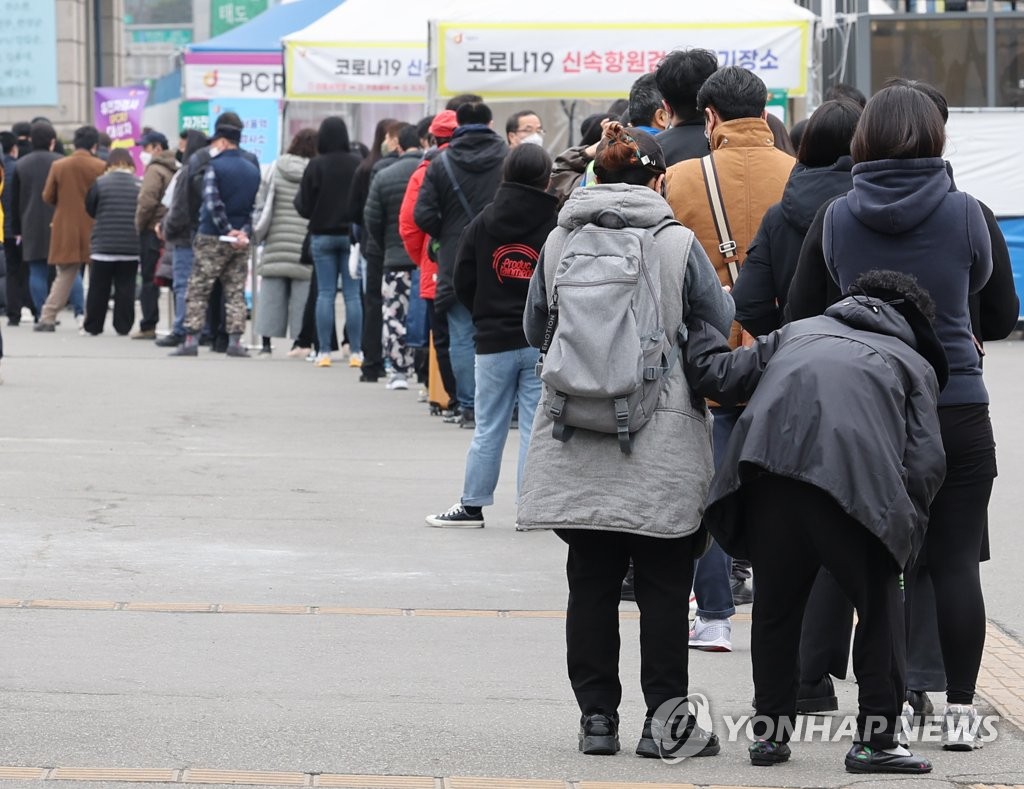 资料图片：3月17日，在首尔站的筛查诊所，市民们排队待检。 韩联社