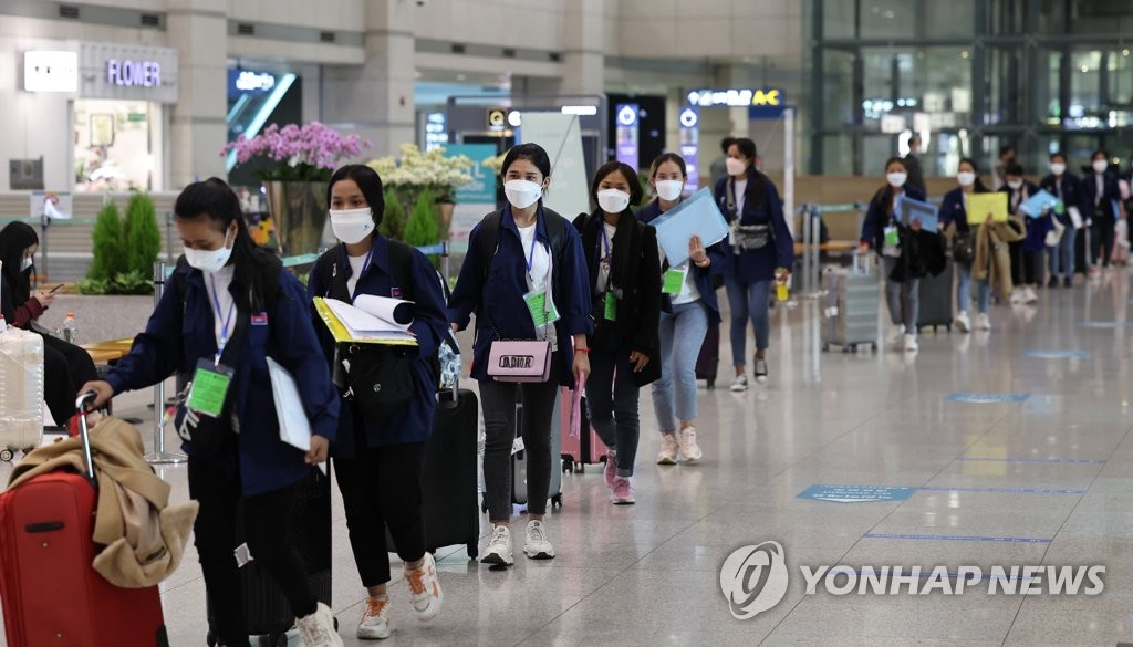 资料图片：3月22日，在仁川国际机场第一航站楼，海外入境人员排起长龙。 韩联社