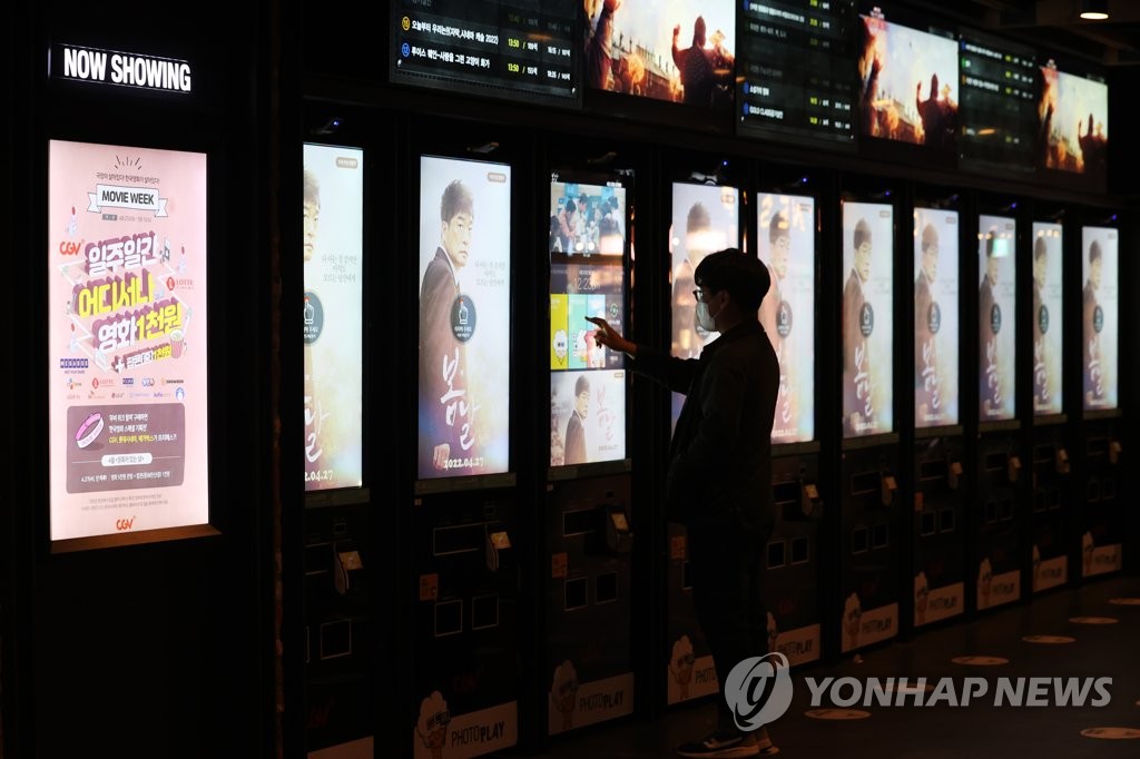资料图片：4月25日，在首尔市星聚汇（CGV）影城龙山店，一位观众正在现场取票。因防疫一度实施的影院内禁食令当天被解除。 韩联社