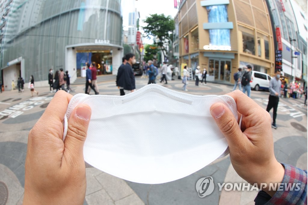 4月29日下午，在首尔市明洞购物街，记者演示摘下口罩畅快呼吸。 韩联社