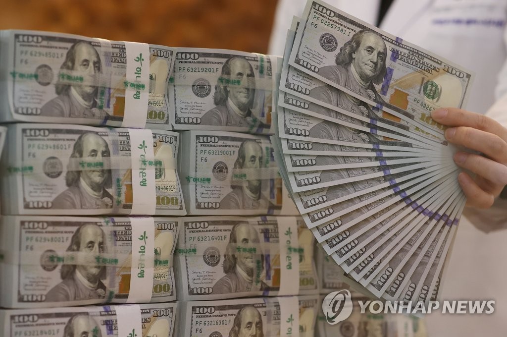 资料图片：5月12日，在首尔市的韩亚银行总行，工作人员展示美元钞票供媒体拍照。 韩联社