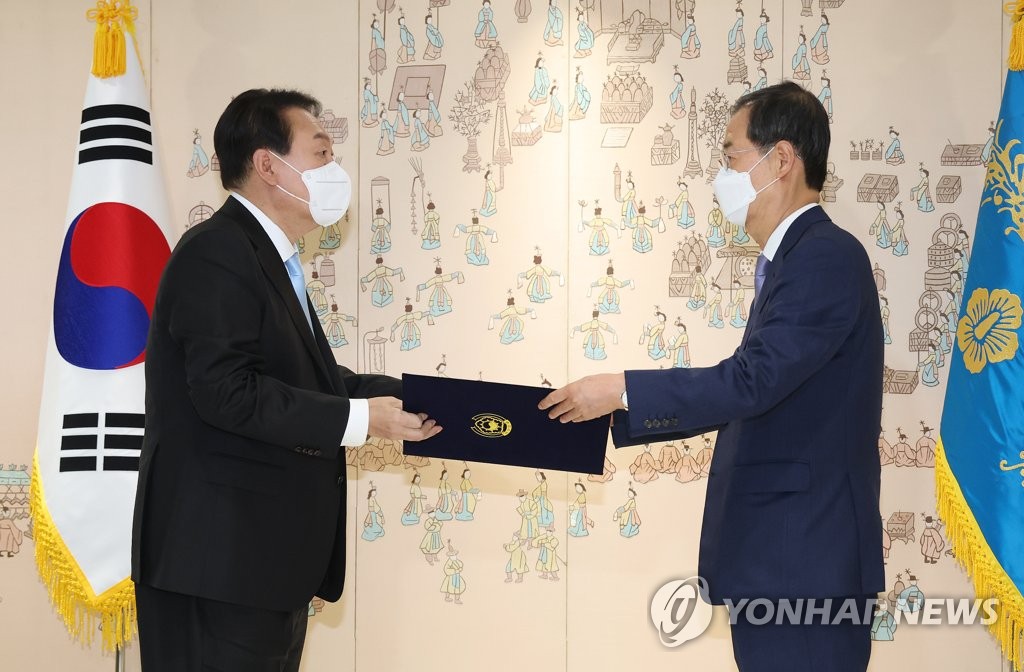 资料图片：5月21日，在首尔龙山总统办公室大楼，韩国总统尹锡悦（左）向新任国务总理韩悳洙颁发任命书。 韩联社