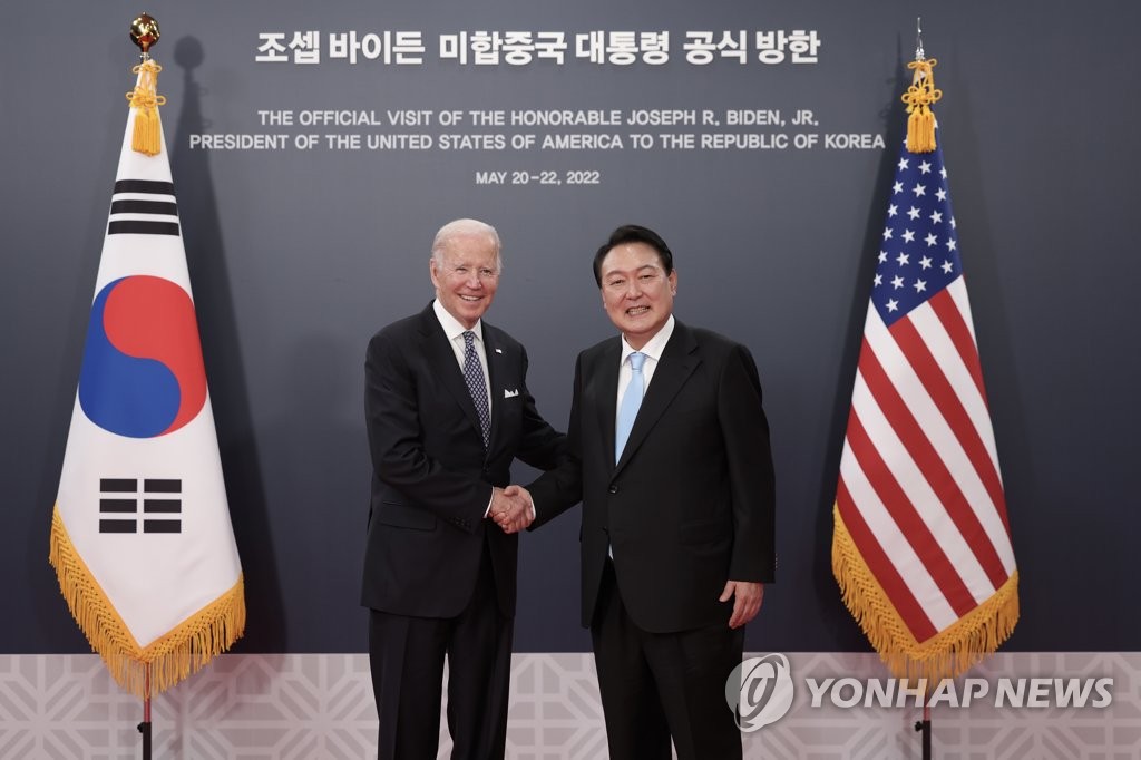 资料图片：5月21日，在位于首尔市龙山区的总统府，韩国总统尹锡悦（右）与美国总统拜登握手合影。 韩联社